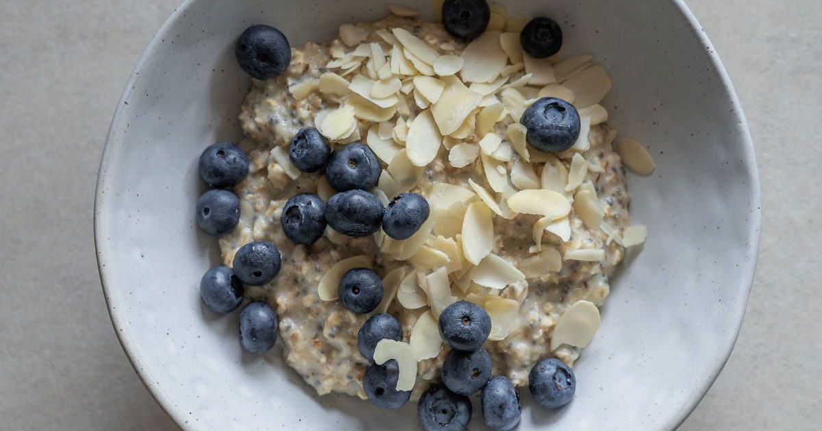 A bowl of oatmeal topped with blueberries and flaked almonds.