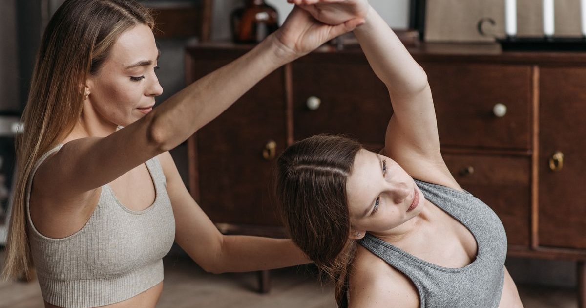 Two women doing a guided stretching and pilates session at home.